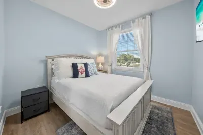 A cheerful blue bedroom with coastal pillows and a window for morning light. A fun room for the kids or anyone who likes a little color.