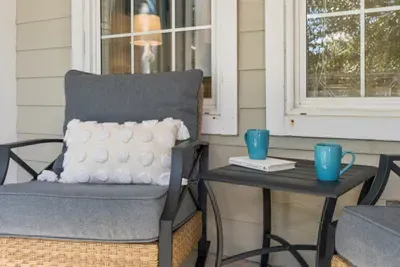 A cozy chair with a pillow and a corner table, ready for a morning mug and a good book on the patio.