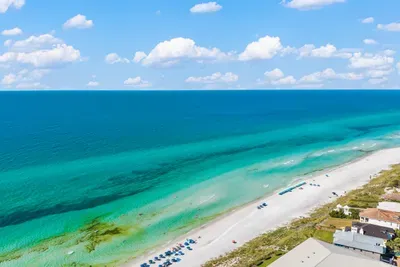 Gulf water in every shade of green and blue, with white sand stretching along the shore. The Blue Mountain Beach public access is about a half mile from the unit.