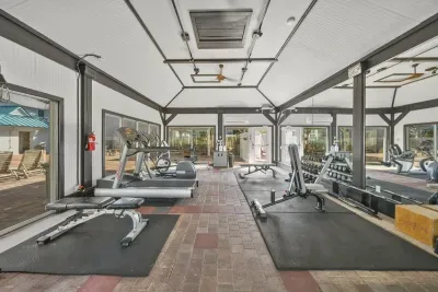 More of the community fitness room, with cardio machines and free weights under a high ceiling and big windows. A workout without the commute.