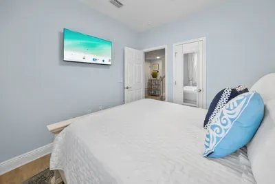 A wall-mounted TV and a calm coastal palette make this blue bedroom an easy place to wind down at the end of the day.