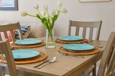 A table set for dinner with fresh tulips and bright dishes. Cook in tonight and you will have the space and the dishes for it.