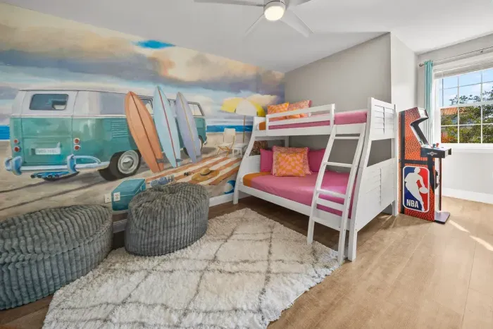 The bunk room is a full kids' hangout: a double on the bottom, a twin on top, a surf van mural and two arcade games, NBA Jam and Ms. Pac-Man/Galaga. Sleeps three, and the kids will want to move in.