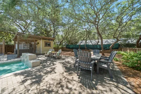 Dine al fresco at the outdoor table, shaded by mature trees and just steps from the pool and grill.