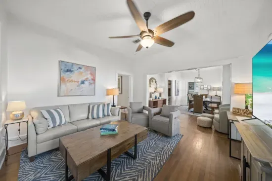 The main living room invites you to unwind, with plush seating, a smart TV, and bright coastal light pouring through the open floor plan.
