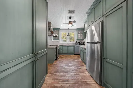 The fully stocked kitchen pairs charming green cabinetry with stainless appliances and everything you need to cook in all week.
