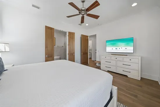 A self-contained retreat on the ground floor — king bed, smart TV, en-suite bath with soaking tub and walk-in shower, and a large walk-in closet.