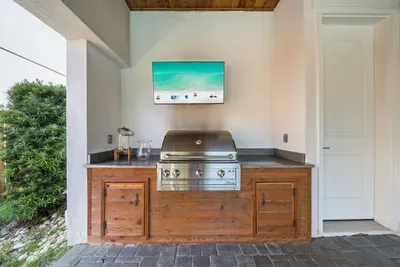 The Artisan propane grill and outdoor TV make the covered patio a full outdoor kitchen — fire it up for dinner while the pool stays right in view.