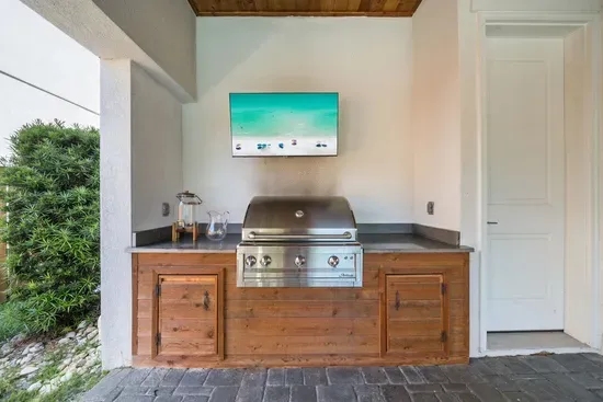 The Artisan propane grill and outdoor TV make the covered patio a full outdoor kitchen — fire it up for dinner while the pool stays right in view.