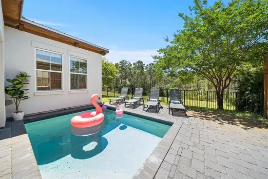 A private resort feel right in the backyard — flamingo floaties, Hollywood loungers, and a full fence so the kids can play freely.