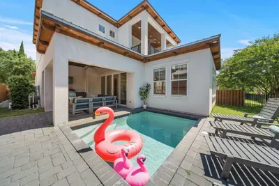 The heated pool is the centerpiece of the backyard — surrounded by loungers, the outdoor kitchen, and the balcony above, it's where everyone ends up.