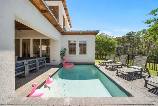 Step out from the living room and you're poolside — the open sliders make the inside and outside feel like one continuous space.