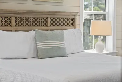 Crisp white linens, a hand-carved driftwood headboard, and soft natural light —  designed for real rest.