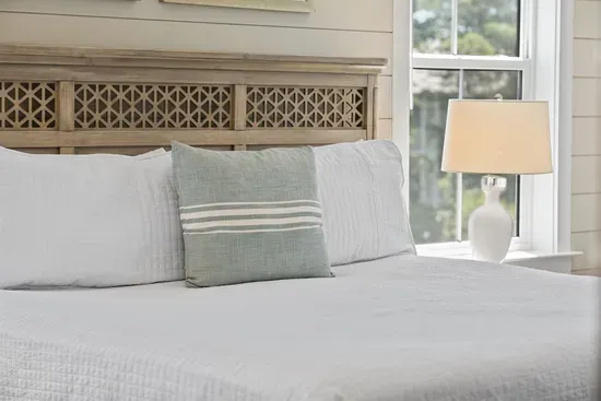 Crisp white linens, a hand-carved driftwood headboard, and soft natural light —  designed for real rest.