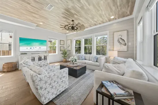 Sink into the sofas after a long beach day — the 65" TV, shiplap walls, and wooded views make the living room as easy to stay in as it is to leave.