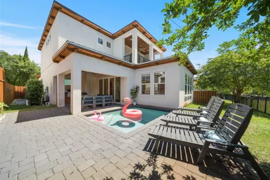 The full picture — heated pool, Hollywood loungers, covered outdoor kitchen, and the master balcony above. Everything you need is right here.