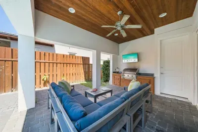 The covered patio is where evenings happen — settle into the sectional, fire up the grill, and let the kids splash in the pool a few steps away.