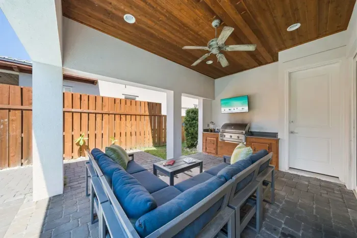 The covered patio is where evenings happen — settle into the sectional, fire up the grill, and let the kids splash in the pool a few steps away.