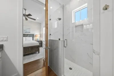 The shared tile shower is all-marble with a frameless glass door — a surprisingly luxurious touch in a shared bath.