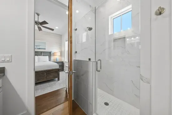The shared tile shower is all-marble with a frameless glass door — a surprisingly luxurious touch in a shared bath.