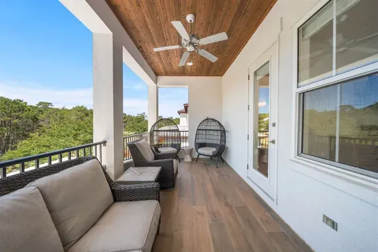 A wide covered balcony with seating for four, shaded by a private wooded canopy — the ultimate quiet spot above the action below.