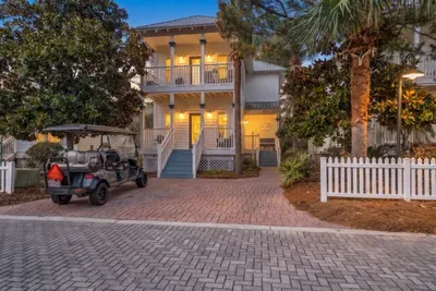 Welcome to 490 Hidden Lake Way, a two-story Santa Rosa Beach retreat with a front porch, a paver driveway and the glow of an Old Florida neighborhood at dusk.