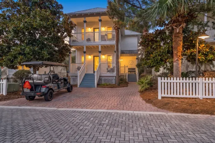 Welcome to 490 Hidden Lake Way, a two-story Santa Rosa Beach retreat with a front porch, a paver driveway and the glow of an Old Florida neighborhood at dusk.