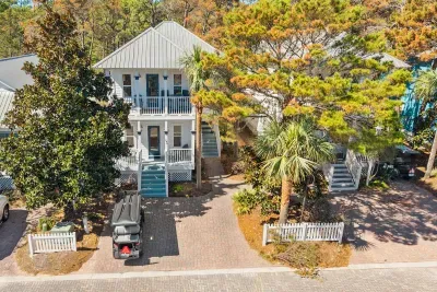 From above, the home sits in a lush, tree-lined Old Florida community, with a paver parking area, a front porch and the LSV ready to go.