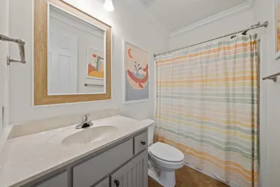 The shared bath has a tub and shower combination and a cheerful striped curtain, easy for kids and adults alike.