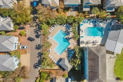 Aerial view of the community pool and lounge deck, steps from the front door and surrounded by a lush canopy of trees.