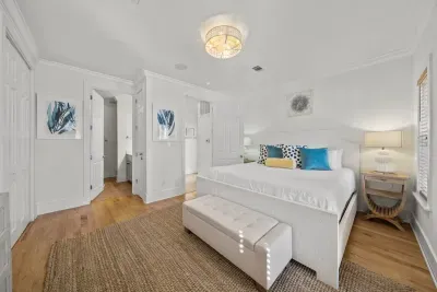 The first-floor master suite has a king bed with a bench at the foot, a closet and a private ensuite bath.