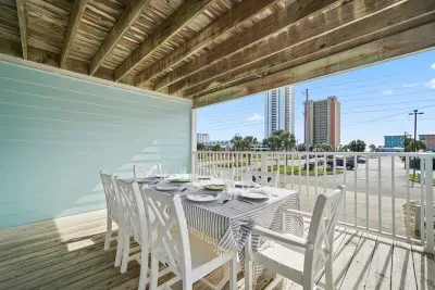 Covered balcony with outdoor dining and partial views toward the coast—an easy spot to enjoy meals or morning coffee.