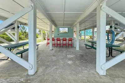 Kick back at your own breezy bar with bold red stools, picnic tables, and a mounted TV.
Perfect for watching the game or sharing drinks after a day in the sun.
*This is a duplex and the outdoor space is shared with guests in the unit next door