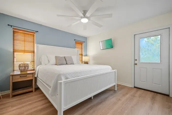 Primary bedroom with a king bed, private walk-out balcony, ensuite bathroom, ceiling fan, and smart TV—ideal for comfort and privacy.
