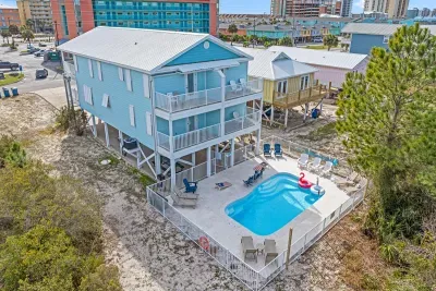 Aerial view of the home featuring a private fenced pool area, multiple balconies, and a spacious outdoor setup just steps from the beach.