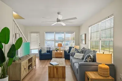 Bright and inviting living area with comfortable seating, large windows, ceiling fan, and smart TV—perfect for relaxing after a beach day.
