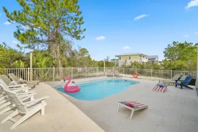 Pool area featuring loungers, pool floats, and a fully fenced deck—great for relaxing and enjoying sunny coastal days.