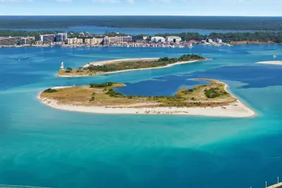 Aerial view of the nearby bay with crystal-clear water, sandy shoreline, and scenic coastal surroundings.