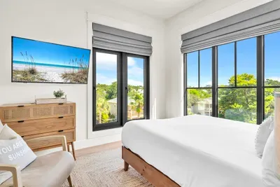Two oversized windows put rooftops, palms, and a lot of sky on display. The kind of room that makes you sleep in.