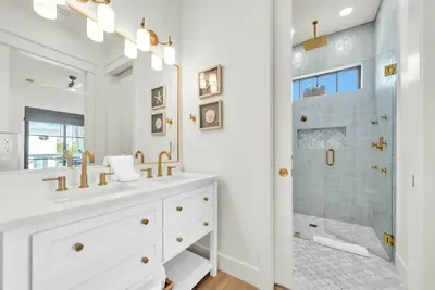 Two sinks means nobody waits. The walk in shower is tiled floor to ceiling with a marble mosaic floor and brass fixtures throughout.