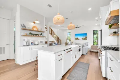 Everything within a few steps. The coffee station, the island, and the range line up along the main level, with the stairs to the bedrooms just beyond.