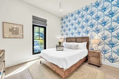 Blue bird of paradise wallpaper gives this bedroom its personality, with a cane headboard, matching nightstands, and treetops out the window.