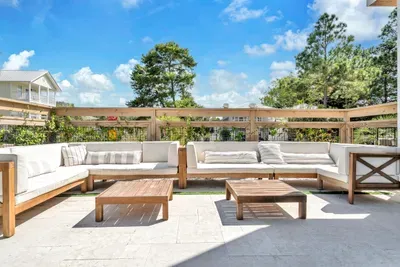 The outdoor sofa is where the day actually happens. Deep cushions, two low tables for drinks, and the pool a few steps away.