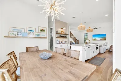 Gather around the long wood table under a coral chandelier, with a ledge of coastal art at your shoulder. Close enough to the kitchen that dinner stays a group effort.