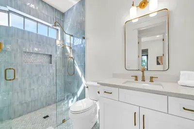 Glossy blue green tile, a glass shower, and a window that keeps the whole room bright. Fresh towels are always stocked.
