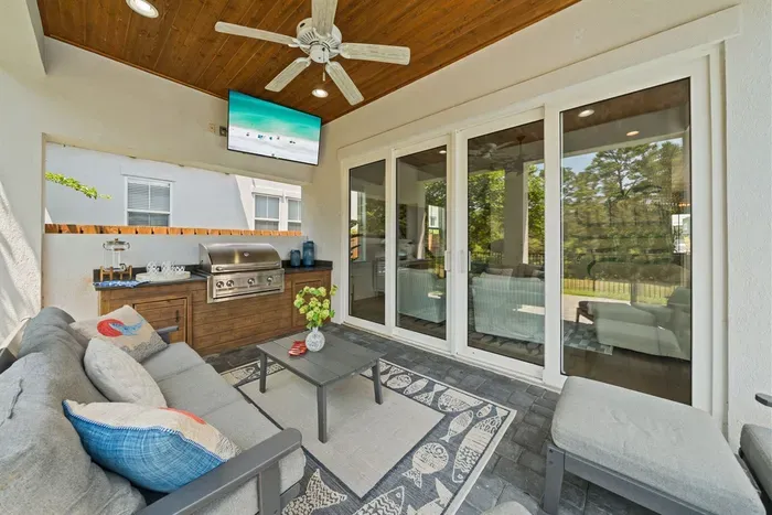 Indoor-outdoor living done right — lounge seating, ceiling fan, and views of the pool just steps away.