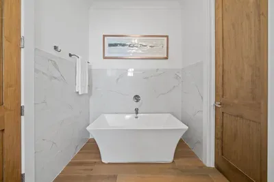 A private ensuite with a freestanding soaking tub and walk-in tile shower — your in-home spa moment. First Floor Bedroom