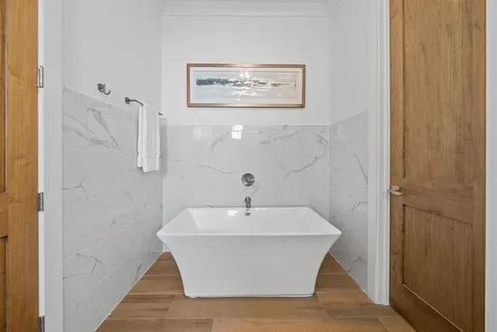 A private ensuite with a freestanding soaking tub and walk-in tile shower — your in-home spa moment. First Floor Bedroom