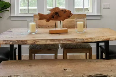 A live edge dining table with bench seating, set under driftwood and candlelight.