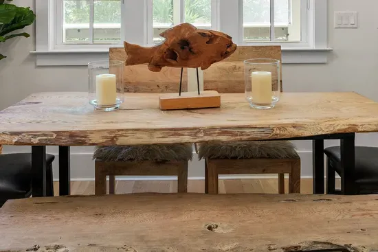 A live edge dining table with bench seating, set under driftwood and candlelight.